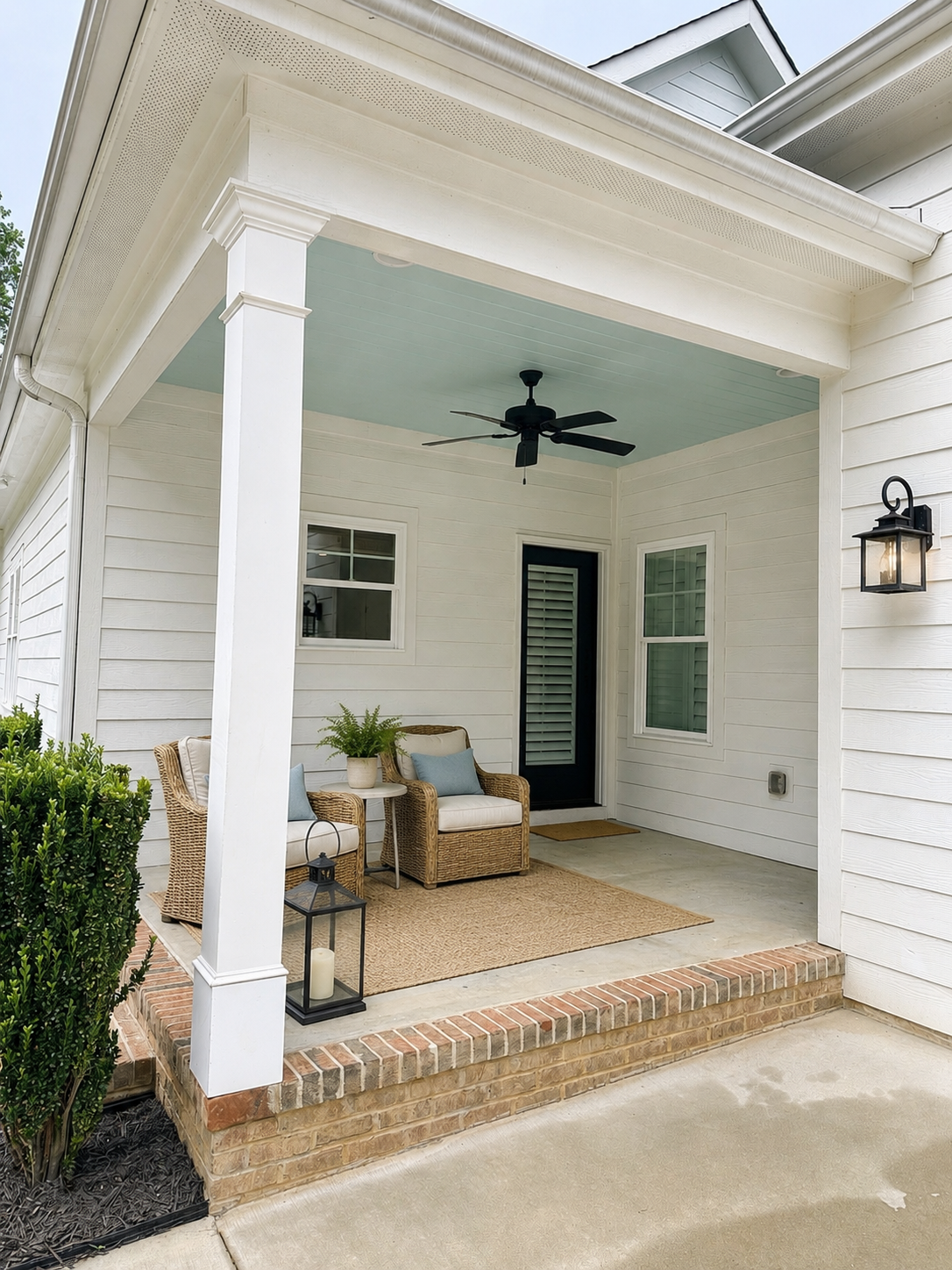 Covered back porch with beadboard ceiling, wicker seating, and black ceiling fan