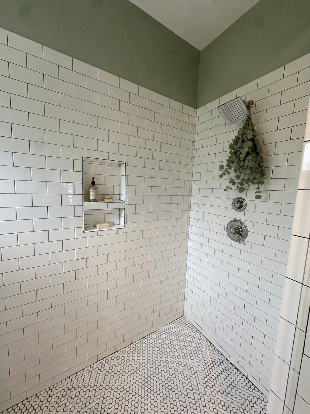 Walk-in shower with built-in niche, subway tile, and hex mosaic floor